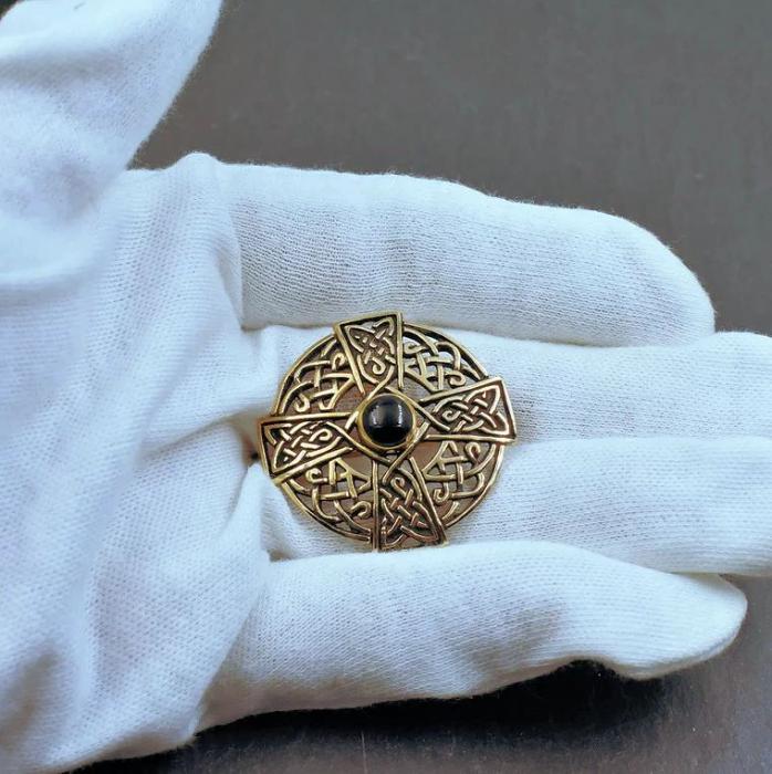Keltische Rundfibel mit keltischem Kreuz aus Bronze auf der Hand